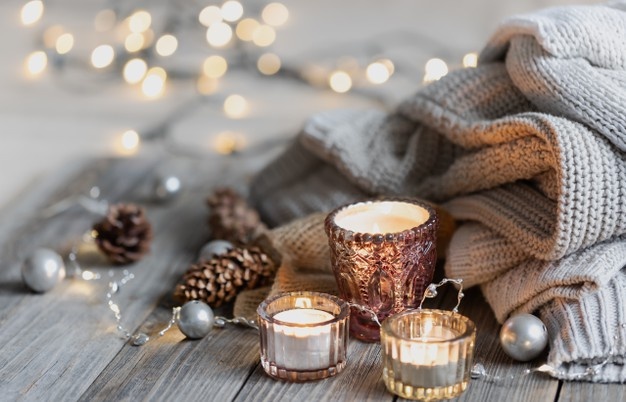 cozy-winter-background-with-burning-candles-decorative-details-knitted-elements-with-bokeh-lights-copy-space_169016-14572